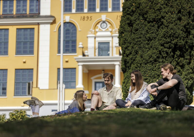 Studenter som sitter fremfor Kaarstad-bygget